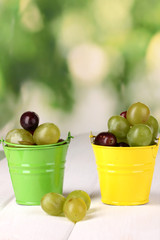 Ripe green and pink grapes in colorful pails