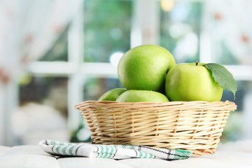 Ripe green apples with leaves in basket,