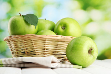 Ripe green apples with leaves in basket,