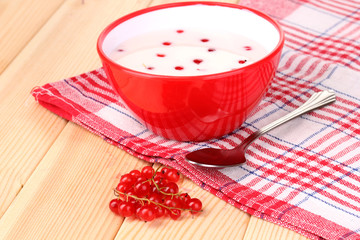 Yogurt with redcurrant on wooden table