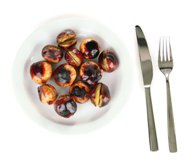 roasted chestnuts in the white plate with fork and knife