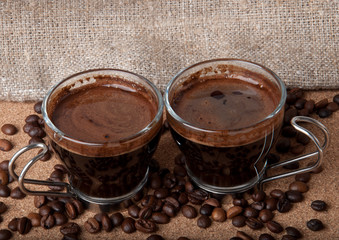 Two cups of black coffee on brown background 