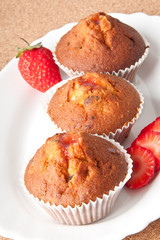 Strawberry muffin on a white plate with a fresh strawberry 