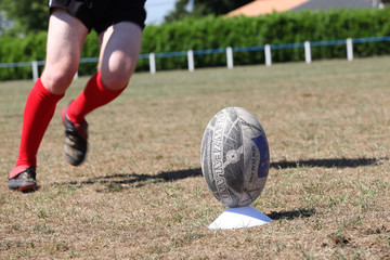 Rugby player kicking ball off plastic tee