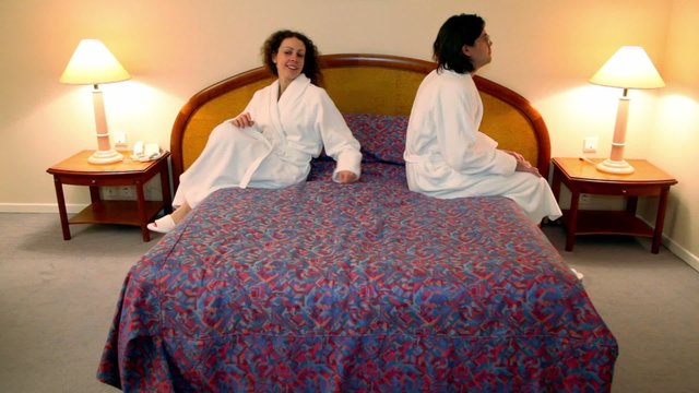 Man with woman in bathrobes come to bedroom and sit on bed