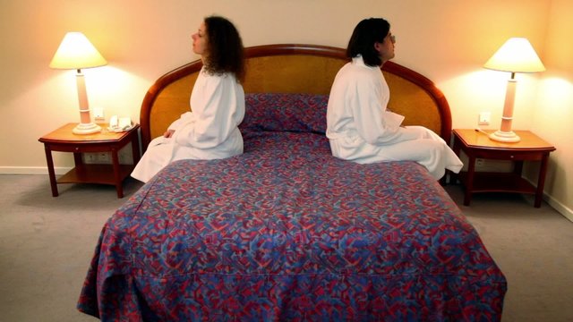 Man with woman come to bedroom, sit and turn off lamps