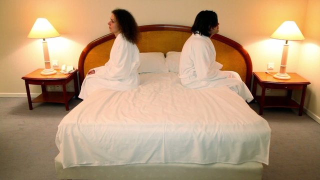 Man with woman in bathrobes come to bedroom and sit on bed