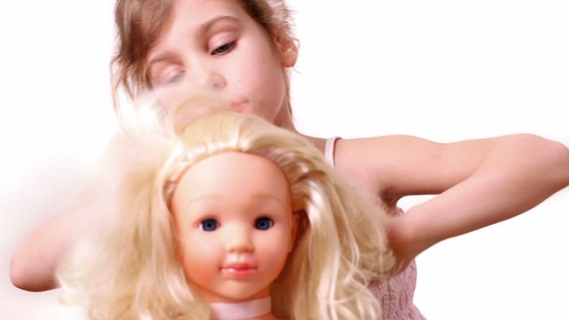 Little girl plays with dolls hairdo, isolated