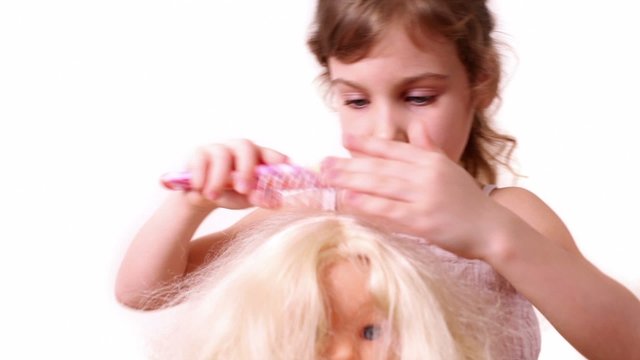 Little girl combs dolls hair, isolated