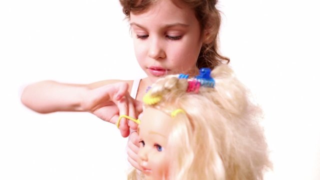 Little girl use elastic band to braid dolls hair, isolated