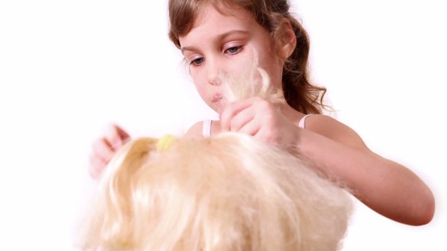 Little girl use elastic band to make dolls hairdo, isolated