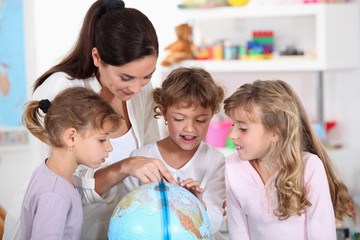 Fototapeta premium woman and children looking at a terrestrial globe
