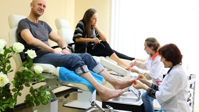 Cosmeticians do hardware pedicure to man and  woman