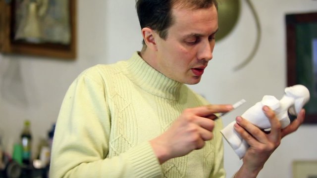 Sculptor holds female figurine in hand and polishes it by file