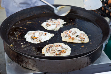 Oysters fried in egg batter being cooked in a pan