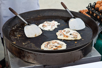 Oysters fried in egg batter being cooked in a pan