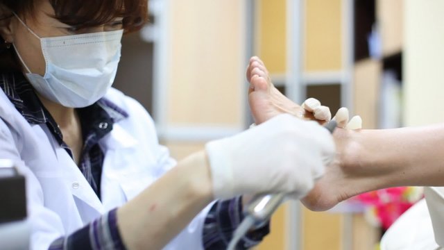 Cosmetician grinds woman heel on doing pedicure in salon