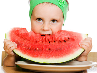 little boy eating a watermelon at a table