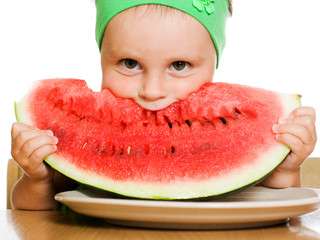 little boy eating a watermelon at a table
