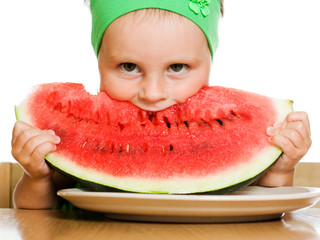little boy eating a watermelon at a table