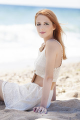 Fototapeta na wymiar Redhead girl sitting at the beach.