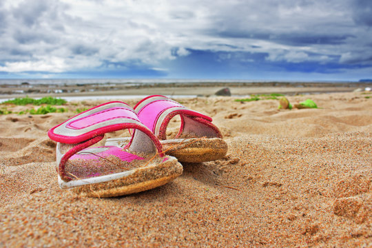 Pink slippers on sandy beach