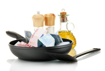 Banknotes in a frying pan with cooking spatula isolated on