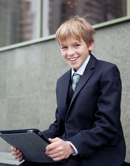 School boy with electronic tablet sitting,