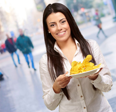 portrait of young woman holding a potato chips plate at city