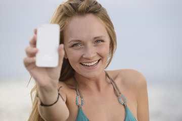 woman taking photo with cellphone on the beach