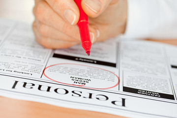 Hand with Red Pen Checking Personals in Newspaper