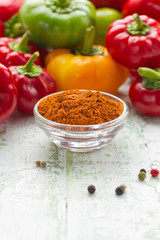 Grinded paprika in a white china bowl and fresh pepper