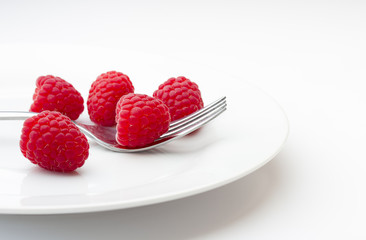 Ripe raspberries on a plate with fork
