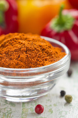 Grinded paprika in a white china bowl and fresh pepper