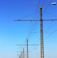 Railroad railway catenary lines against clear blue sky.