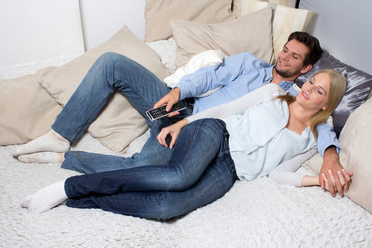 Young Couple lying On A Couch and watching TV