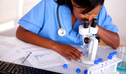 Pretty nurse working with a microscope