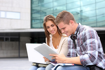 Students using tablet outside university building