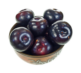 Plums in bowl on white background