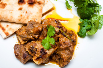 Lamb curry cirrander and Naan close up on a white plate