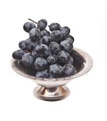 Branch of black grape in metal bowl isolated on white background