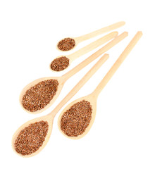 flax seeds in wooden spoons on white background close-up