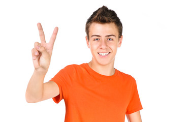 Fototapeta premium smiling teen boy shows victory sign isolated over white