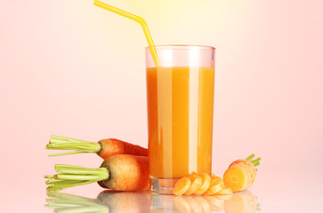 glass of carrot juice on pink-yellow background