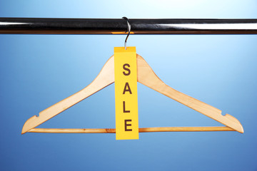 wooden clothes hanger as sale symbol on blue background.