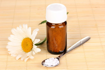 medicine bottle with tablets and flower on bamboo mat