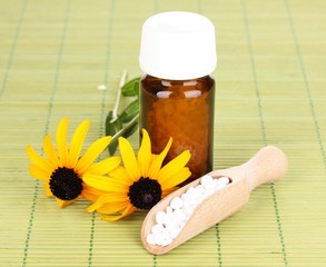 medicine bottle with tablets and flowers on bamboo mat