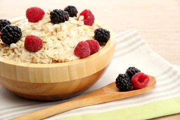 tasty oatmeal with berries, on wooden table