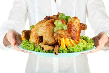Chef holding a plate of baked chicken with fruit and spices