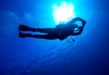 Silhouette of diver with sun disk behind